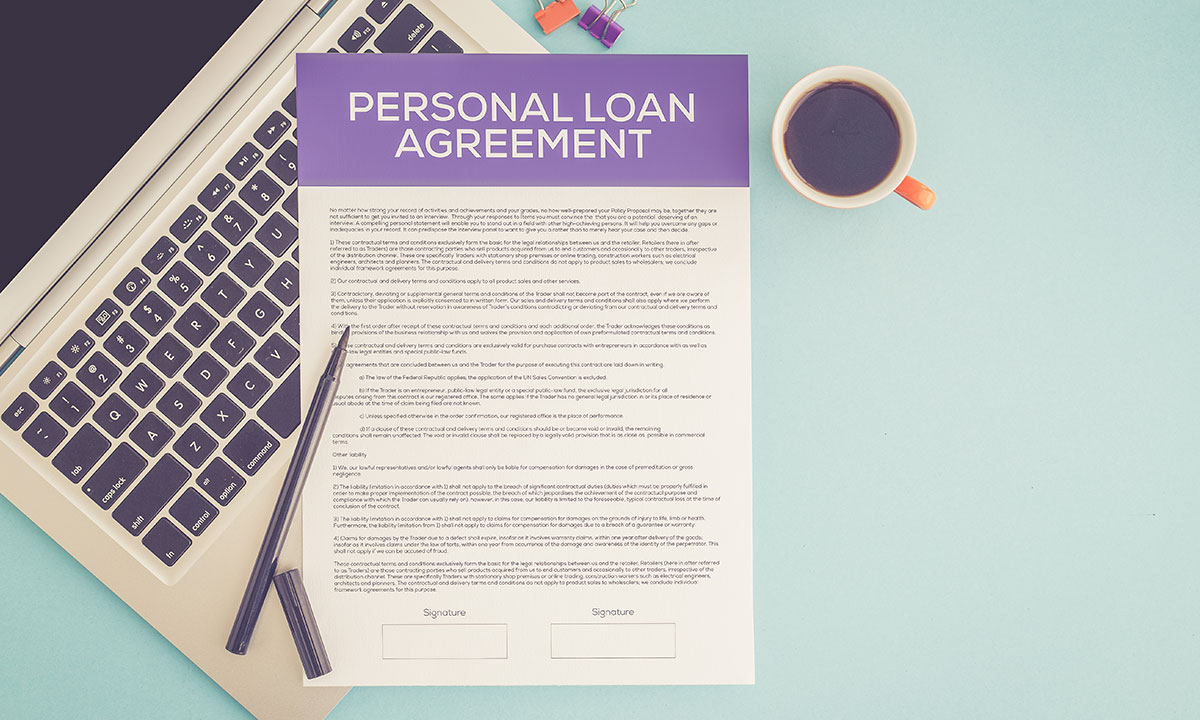 Personal loan agreement on a desk, laptop, pen and cup of coffee