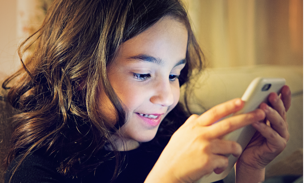 A young girl plays on her mobile phone