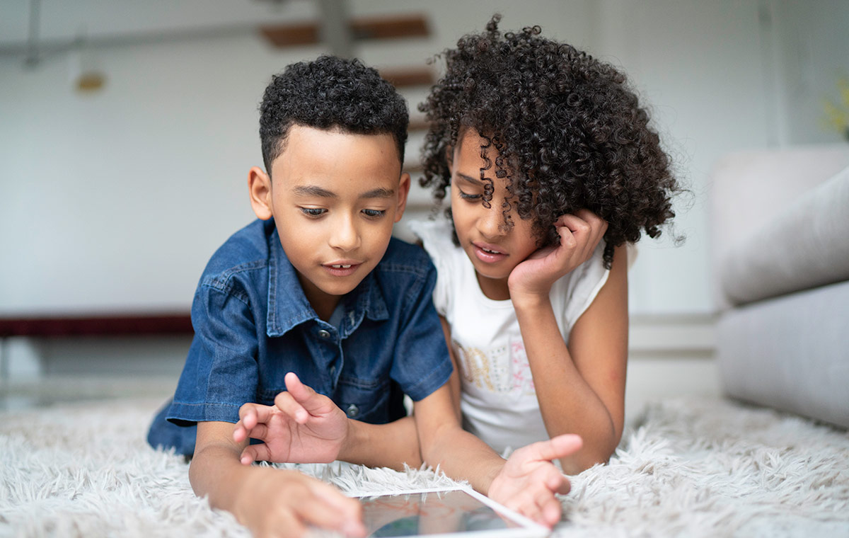 Two children play together on an iPad