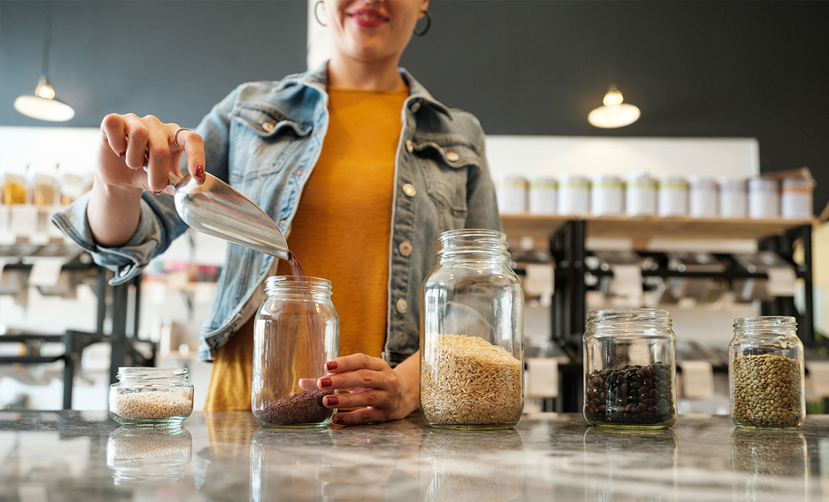 A girl fills reusable glass jars with grains and pulses