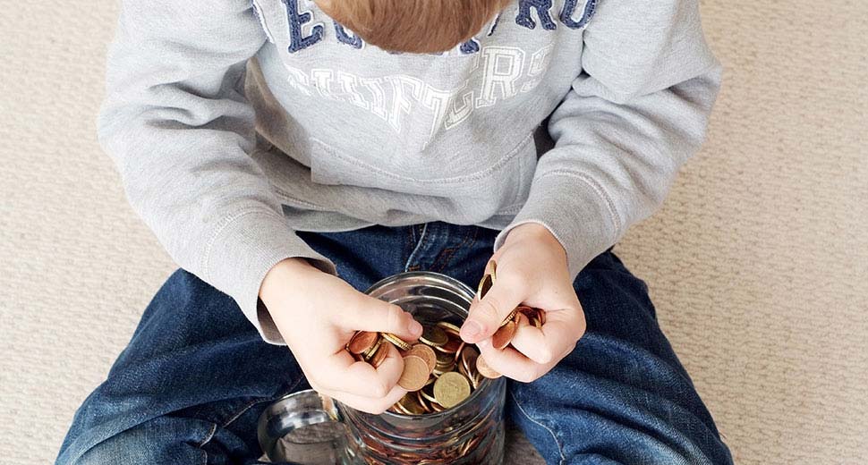 Young boy counts money from a savings jar