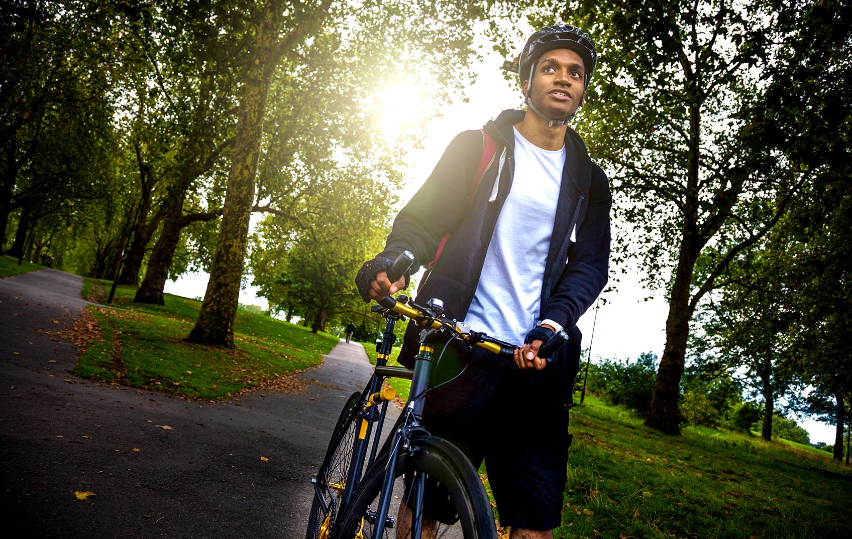 A student pushes his bike through a park