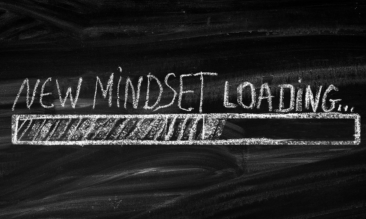 A blackboard with text written in chalk saying NEW MINDSET LOADING...